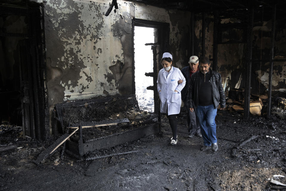 People walk inside a building, destroyed by shelling by Armenian forces in Barda, Azerbaijan, Monday, Oct. 5, 2020. The fighting between Armenian and Azerbaijani forces over the separatist territory of Nagorno-Karabakh resumed Monday, with both sides accusing each other of launching attacks. The region lies in Azerbaijan but has been under the control of ethnic Armenian forces backed by Armenia since the end of a separatist war in 1994. (Unal Cam/DHA via AP)