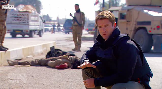 Behind reporter Denham Hitchcock, three dead bodies lie on the street. It's a common sight in Mosul.