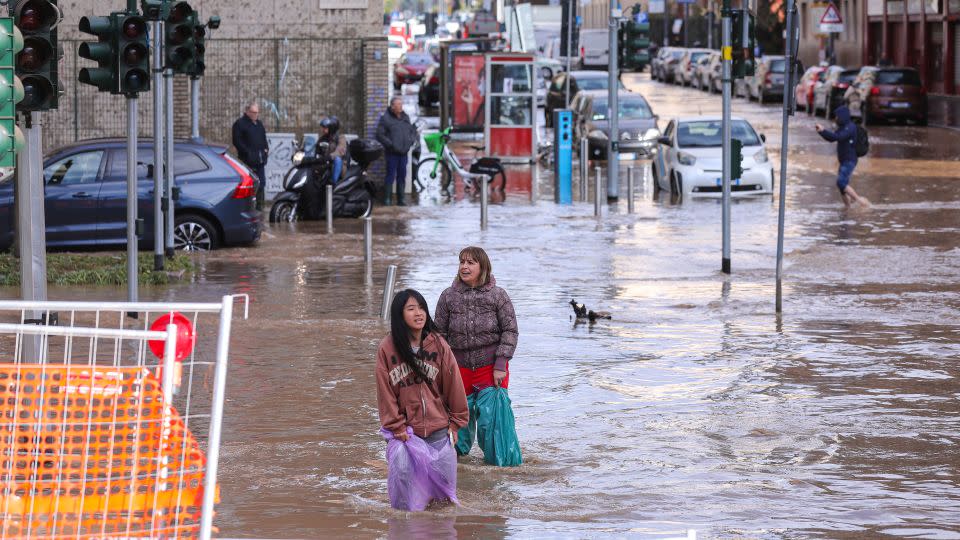 Two women at a flooded intersection in Milan after a violent storm hit the city on October 31, 2023. - Vasile Mihai-Antonio/Getty Images