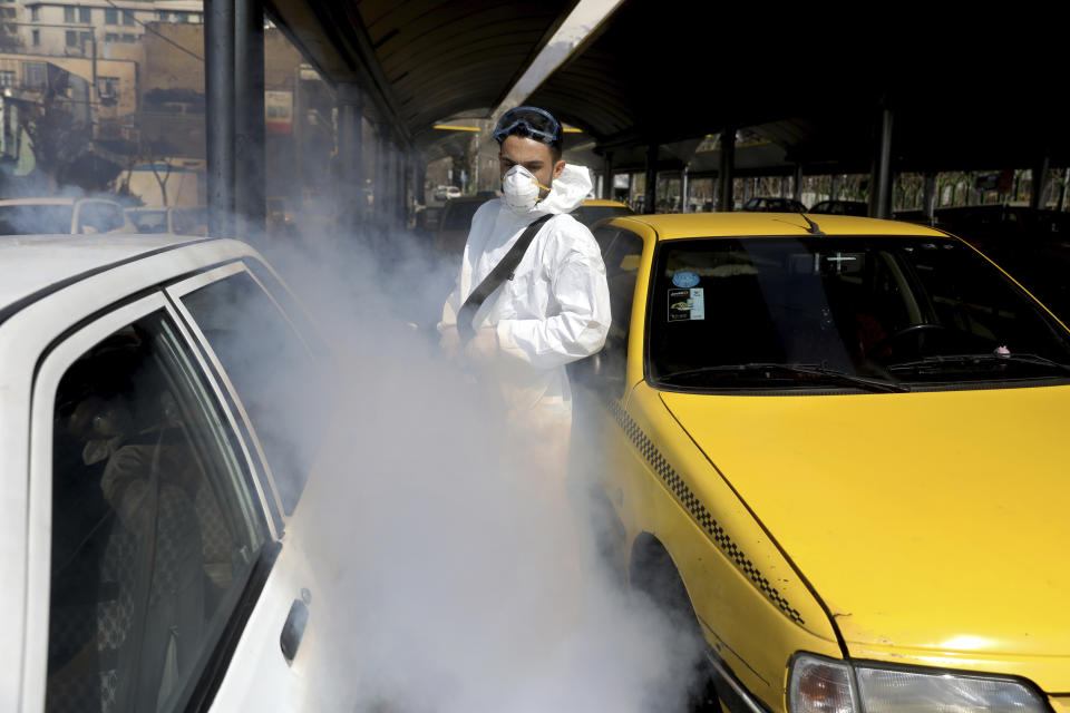 A firefighter disinfects a taxi stand to help prevent the spread of the new coronavirus in northern Tehran, Iran, Friday, March, 6, 2020.  A Health Ministry spokesman warned authorities could use unspecified “force” to halt travel between major cities.(AP Photo/Ebrahim Noroozi)