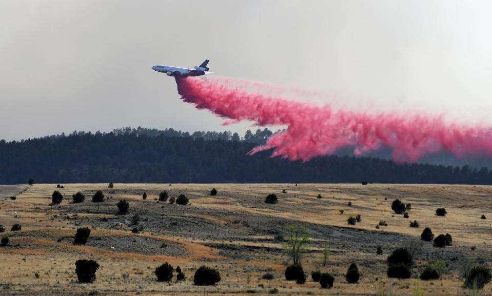 A firefighting airplane drops slurry on a wildfire near Las Vegas, N.M., on Tuesday, May 3, 2022. Flames raced across more of New Mexico's pine-covered mountainsides Tuesday, charring more than 217 square miles (562 square kilometers) over the last several weeks. (AP Photo/Thomas Peipert)