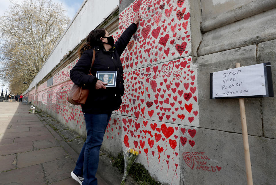 Familiy members bereaved by Covid-19 mark the completion of the approximately 150,000 hearts being painted onto the National Covid Memorial Wall, on the Thames Embankment opposite the Houses of Parliament in London, Thursday, April 8, 2021. Bereaved families want the wall of painted hearts to remain a site of national commemoration and are asking the Prime Minister to help make the memorial permanent. (AP Photo/Frank Augstein)