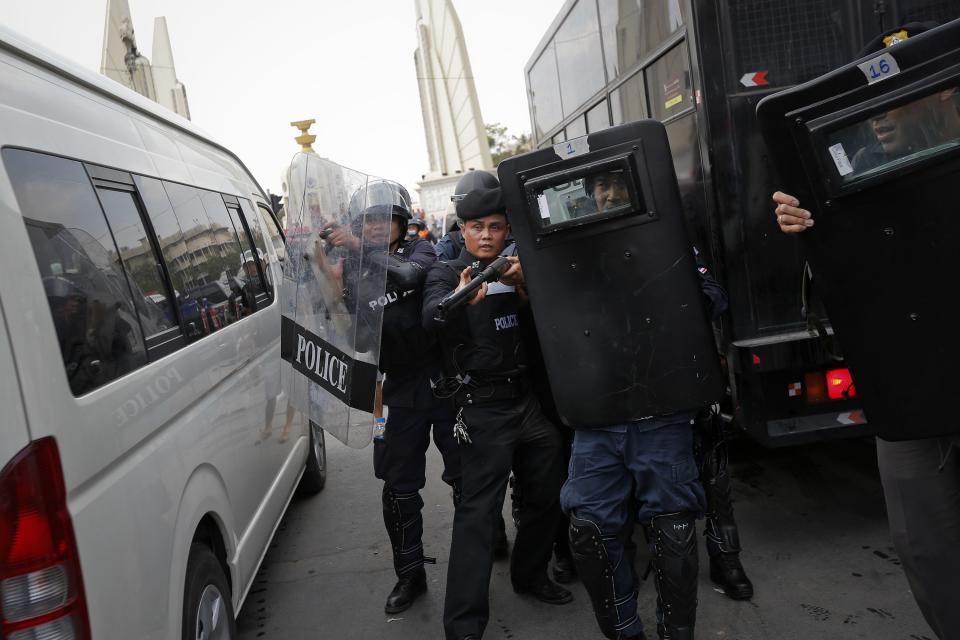 Policeman hold their weapons ready as they pull back during clashes with anti-government protesters near Government House in Bangkok