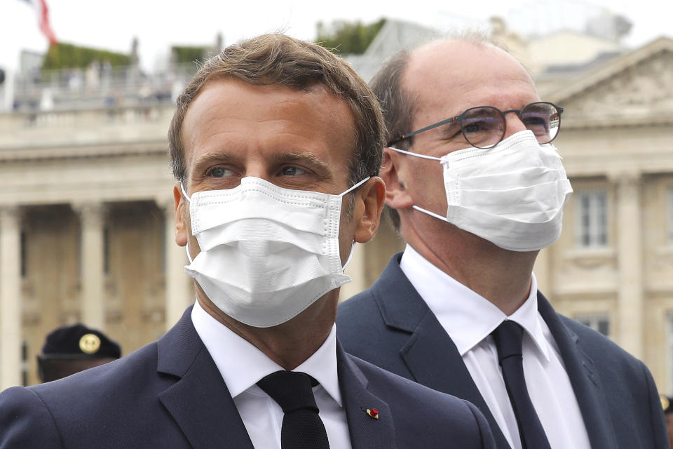 France's President Emmanuel Macron, left, and France's Prime Minister Jean Castex, wear face mask, at the end of the Bastille Day military parade, Tuesday, July 14, 2020 in Paris. Nurses in white coats played the starring role in France's Bastille Day ceremonies Tuesday instead of uniformed soldiers, as the usual grandiose military parade was recalibrated to honor medics who died fighting COVID-19, supermarket cashiers, postal workers and other heroes of the pandemic. (Ludovic Marin, Pool via AP)
