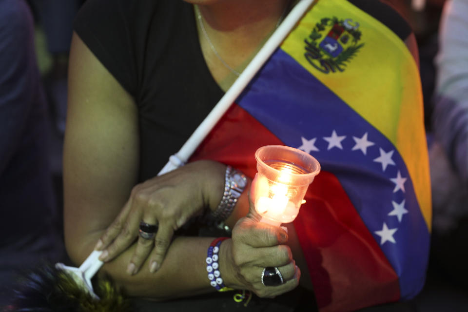 An opponent to Venezuela's President Nicolas Maduro holds a candle during a vigil for those killed in street fighting over the past week in Caracas, Venezuela, Sunday, May 5, 2019. Opposition leader Juan Guaid called in vain for a military uprising to overthrow President Nicolas Maduro, and five people were killed in clashes between protesters and police. (AP Photo/Martin Mejia)