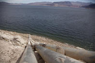 FILE - Pipes extend into Lake Mead well above the high water mark near Boulder City, Nev., on March 23, 2012. The sight of fountains, swimming pools, gardens and golf courses in Western cities like Phoenix, Los Angeles, Las Vegas, San Diego and Albuquerque can seem jarring with drought and climate change tightening their grip on the region. But Western water experts say they aren’t necessarily cause for concern. Many Western cities over the past three decades have diversified their water sources, boosted local supplies, and use water more efficiently now than in the past. (AP Photo/Julie Jacobson, File)