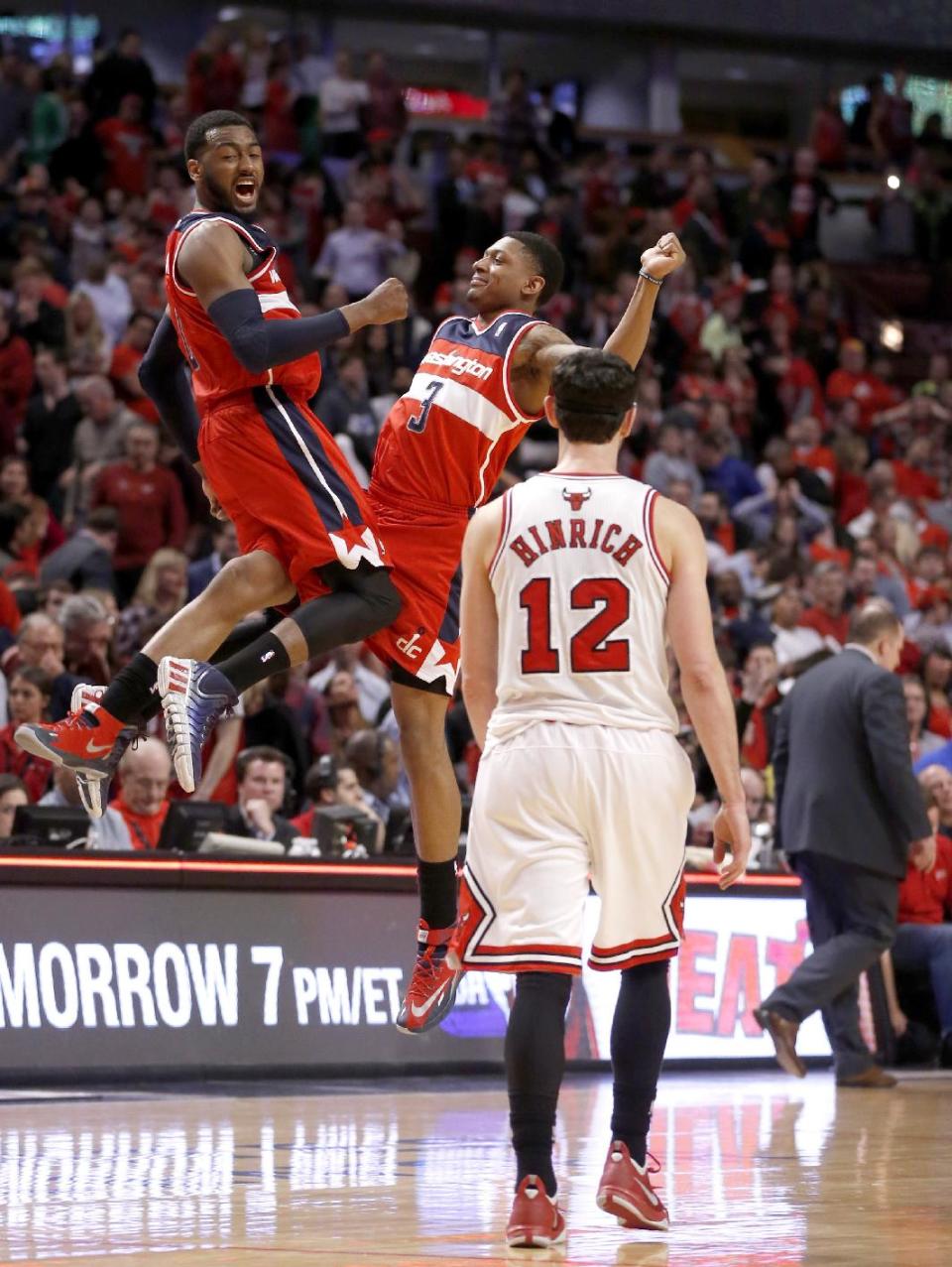 Washington Wizards guard John Wall, left, and Bradley Beal celebrate the Wizards' 101-99 win as Chicago Bulls guard Kirk Hinrich walks off the court after missing two free throws during the overtime period of Game 2 in an opening-round NBA basketball playoff series Tuesday, April 22, 2014, in Chicago. (AP Photo/Charles Rex Arbogast)