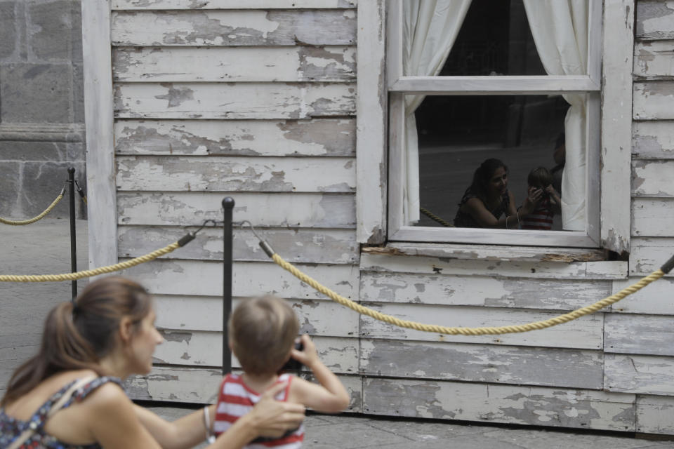 Alice Ridolfi, from Verona, helps her two-year-old son Leone take pictures of the house of U.S. civil rights campaigner Rosa Parks, rebuilt by artist Ryan Mendoza for public display in Naples, Italy, Tuesday, Sept. 15, 2020. The rundown, paint-chipped Detroit house where Parks took refuge after her famous bus boycott is going on display in a setting that couldn't be more incongruous: the imposing central courtyard of the 18th century Royal Palace. (AP Photo/Gregorio Borgia)