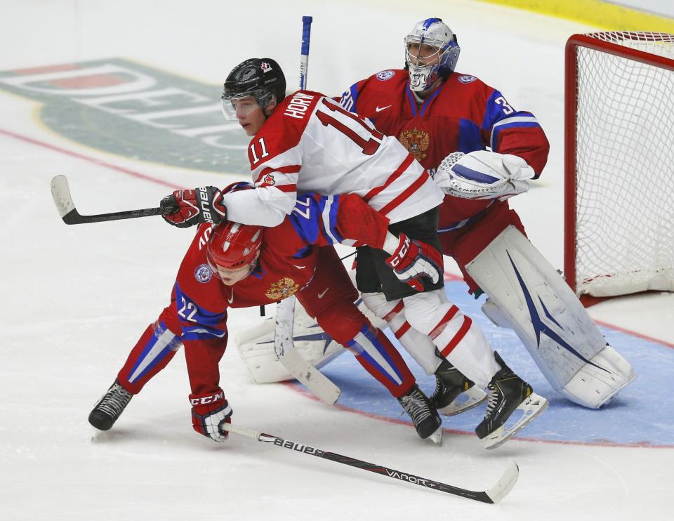 Canada's Bo Horvat (C) leans over Russia's Andrei Mironov (L) as Russia's goalie Andrei Vasilevski tries to follow the play during the second period of their IIHF World Junior Championship ice hockey game in Malmo, Sweden, January 5, 2014. REUTERS/Alexander Demianchuk (SWEDEN - Tags: SPORT ICE HOCKEY)