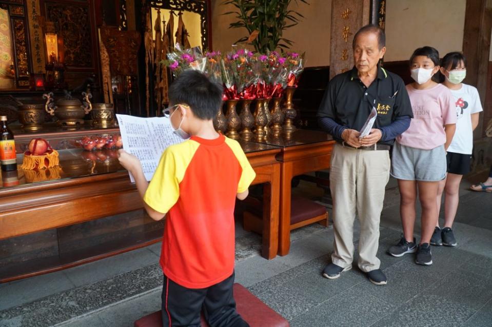 ３名小學生祝禱生在義民廟廟公林邦雄（左２）的指導下，全程用海陸腔客語唸祝禱文。（記者彭新茹攝）