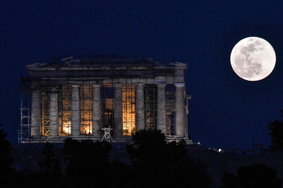 The supermoon rises next to the Parthenon Temple at the Acropolis archaeological site on Tuesday.