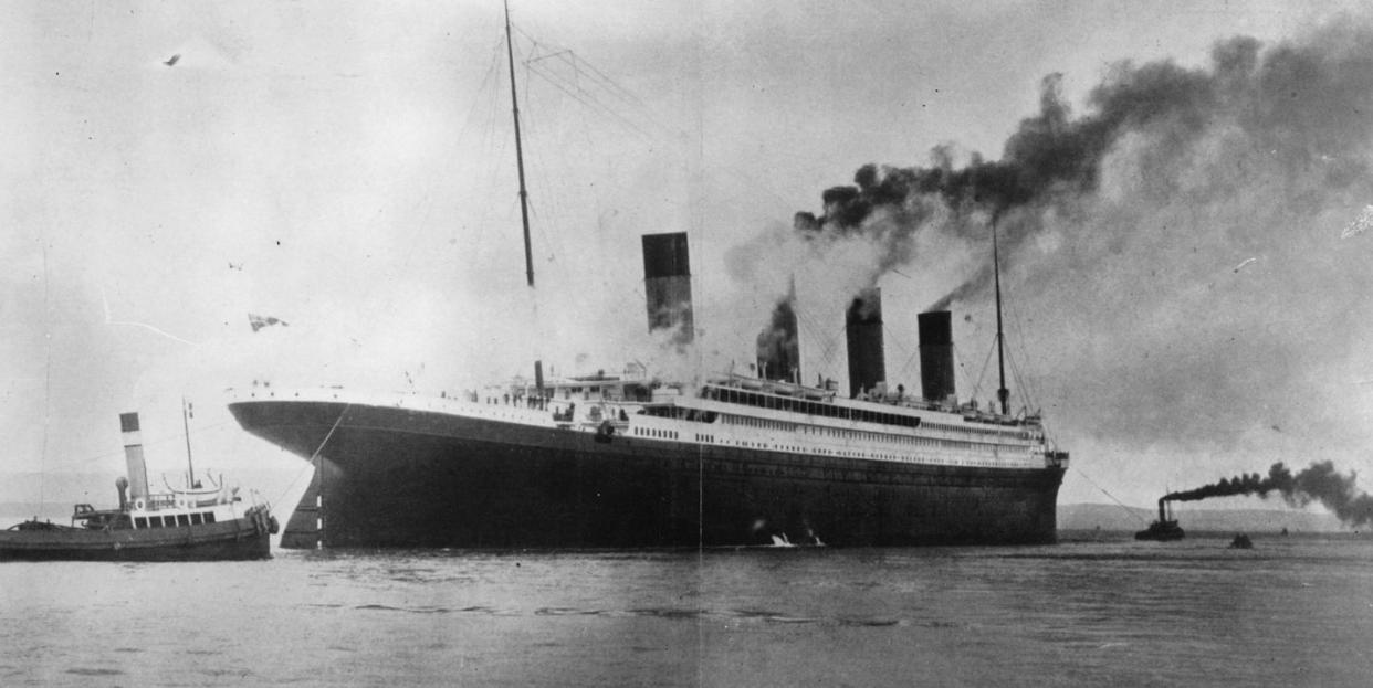 a black and white photo of the titanic next to smaller boats in the water