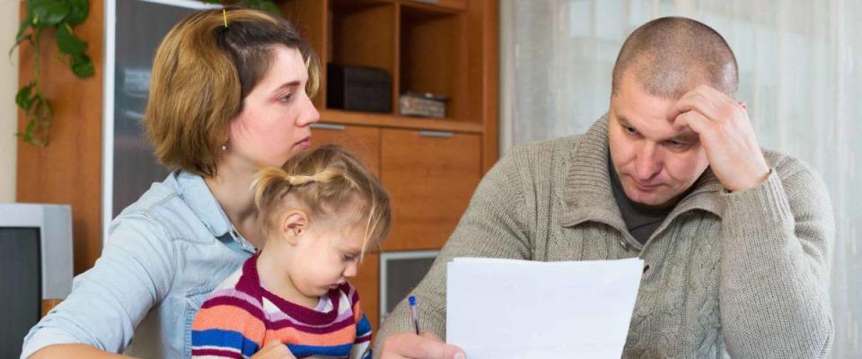 Serious couple with little girl counting budget at home