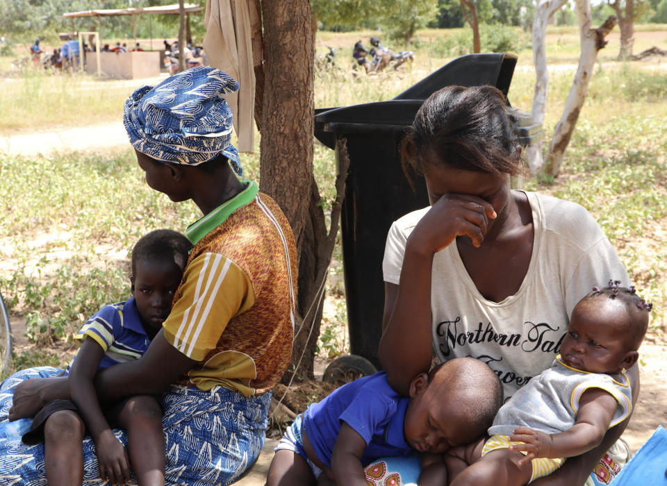 Two women sit outside a small clinic in Gampela village on the outskirts of Burkina Faso's capital, Ouagadougou, Saturday Oct. 10, 2020, waiting to take their children to the doctor. They sometimes wait up to four hours to get medical help. The public health clinic responsible for serving approximately 11,000 people, did not have a working fridge for almost a year. The vaccine cold chain hurdle is just the latest disparity of the pandemic weighted against the poor, who more often live and work in crowded conditions that allow the virus to spread, have little access to medical oxygen vital to COVID-19 treatment, and whose health systems lack labs, supplies or technicians to carry out large-scale testing. (AP Photo/Sam Mednick)