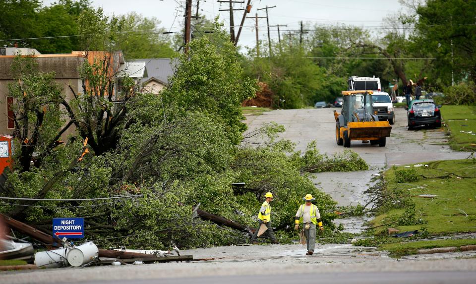 Workers on Thursday clear trees toppled by Wednesday night's tornado from E Oaks Avenue near N Milt Phillips Avenue in Seminole.