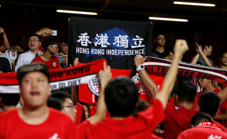 Football Soccer - Hong Kong v Malaysia - AFC Asian Cup Qualifiers - Hong Kong, China – October 10, 2017 - Hong Kong fans hold a protest banner and turn their backs during Chinese national anthem. REUTERS/Bobby Yip