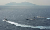 Japan Coast Guard vessels sail along with Chinese surveillance ship Haijian No. 66, center, near disputed islands called Senkaku in Japan and Diaoyu in China, seen in background, in the East China Sea, on Monday, Sept. 24, 2012. (AP Photo/Kyodo News) JAPAN OUT, MANDATORY CREDIT, NO LICENSING IN CHINA, HONG KONG, JAPAN, SOUTH KOREA AND FRANCE