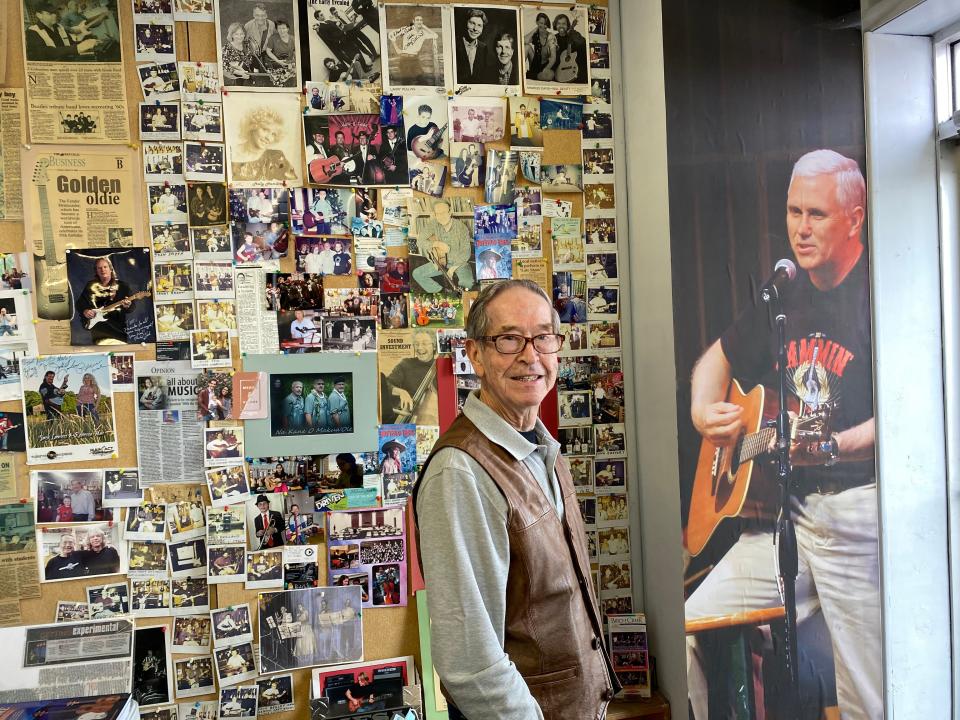 Music shop owner Tom Pickett stands in front of a life size photograph of Mike Pence in the doorway of his shop in Columbis, Indiana. Mr Pickett taught the former vice president how to play guitar when he was a senior in high school.  (Richard Hall / The Independent )