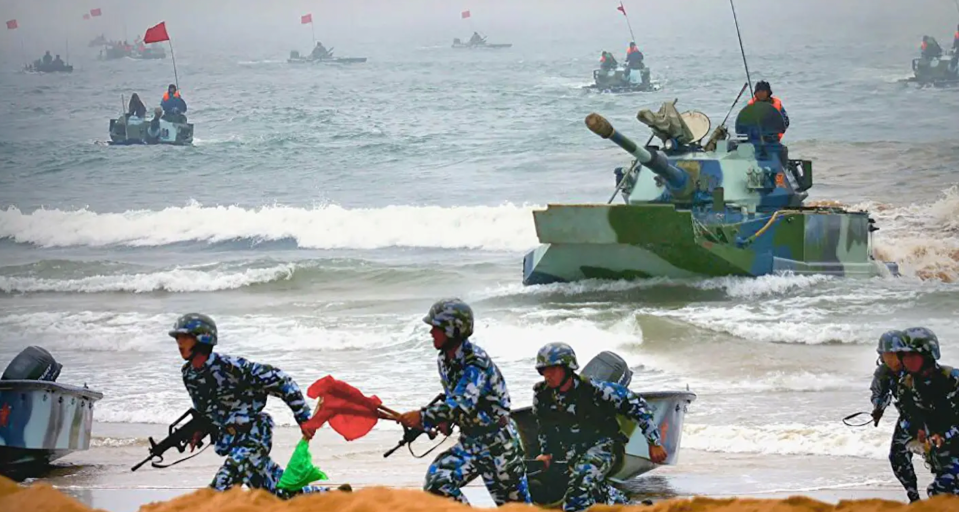 Chinese marines race ashore accompanied by amphibious tanks during a beach assault exercise. <em>PLA</em>