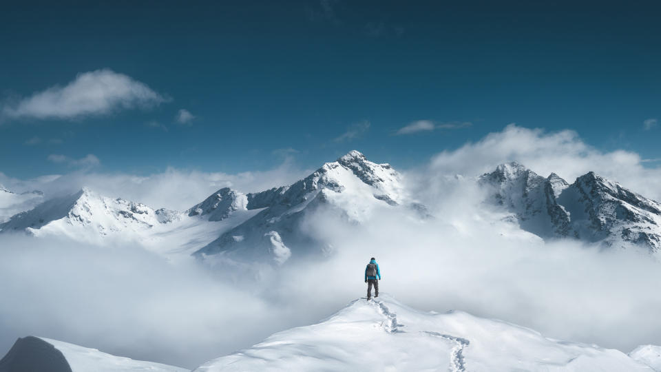 A hiker standing on the top of a snowcapped mountain peak.jpg