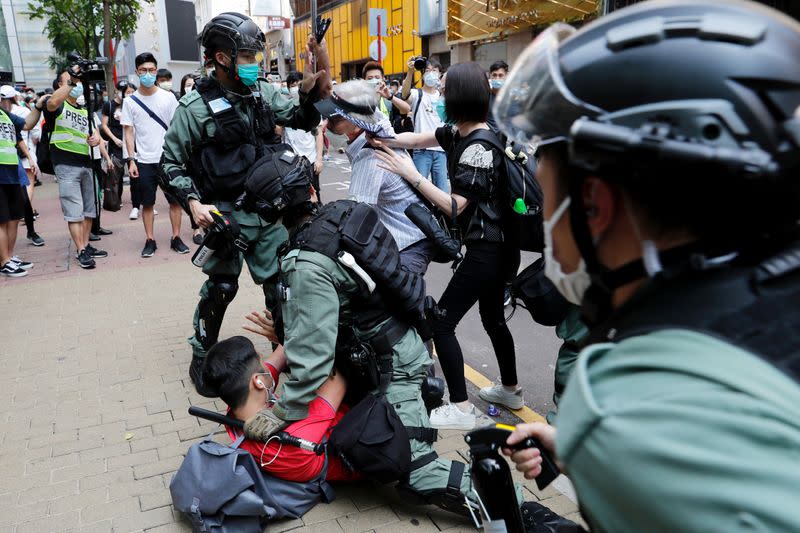 Anti-government demonstrators scuffle with riot police during a lunch time protest as a second reading of a controversial national anthem law takes place in Hong Kong