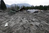 Footprints from searchers remain in mud at the edge of a deadly mudslide Tuesday, March 25, 2014, in Oso, Wash. At least 14 people were killed in the 1-square-mile slide that hit in a rural area about 55 miles northeast of Seattle on Saturday. Several people also were critically injured, and homes were destroyed. (AP Photo/Elaine Thompson)