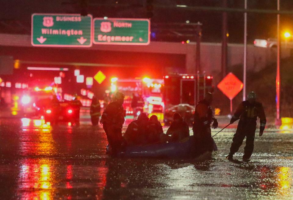 Firefighters use a boat to ferry motorists to higher ground after they were stranded in high water on Route 13 at the I-495 interchange late Tuesday evening, January 9, 2024 as a storm brings high winds and heavy rain to Delaware.