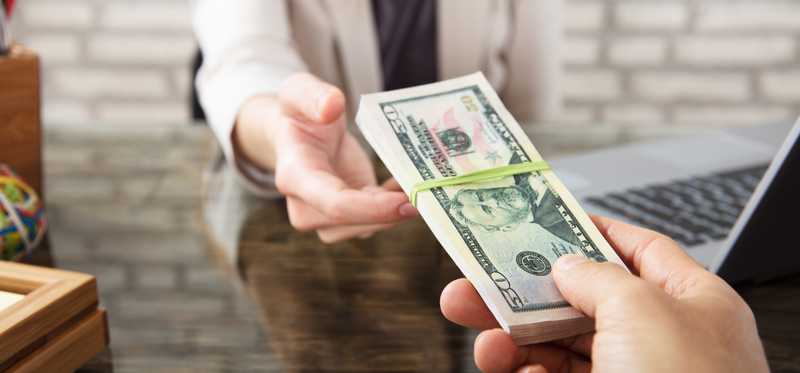 A woman is handed a stack of cash.