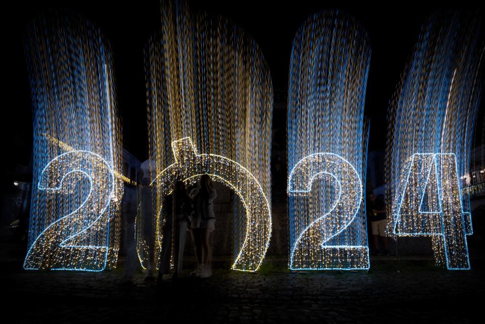 People pose for a picture next to a sign celebrating the upcoming new year in Ouro Preto, Minas Gerais state, Brazil (AFP via Getty Images)