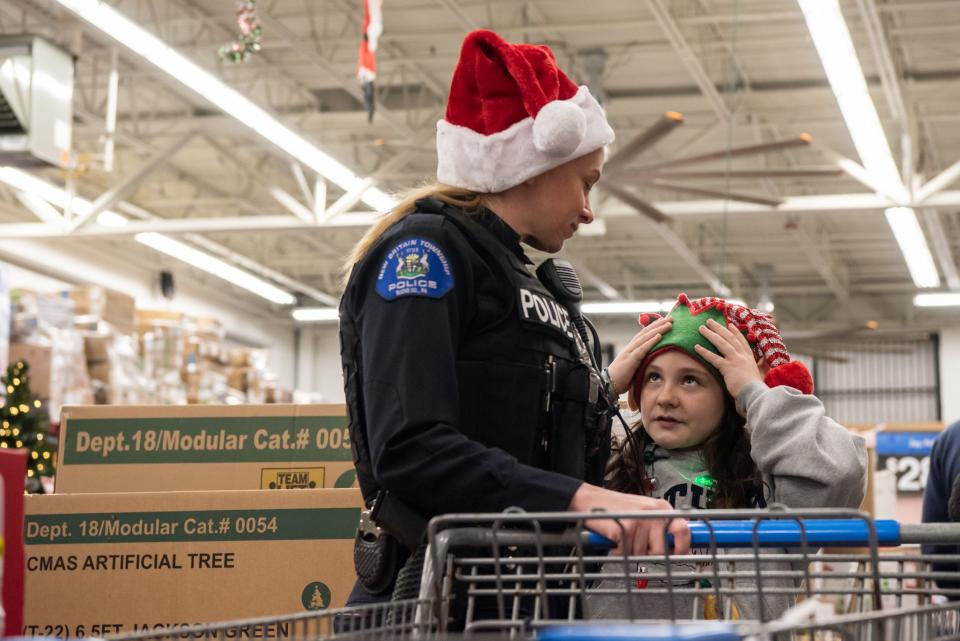 New Britain Township Police Ofc. Kate Peffall, left, and Jilian Kallatch, 10, of Pipersville, wait in line to checkout during Plumstead Township Police Department's 5th annual Shop with a Cop event at Walmart in Hilltown Township on Tuesday, December 8, 2021. Funded by community donations, the program paired law enforcement officers from 11 local departments with more than 100 kids to help them shop for presents for themselves and their families.