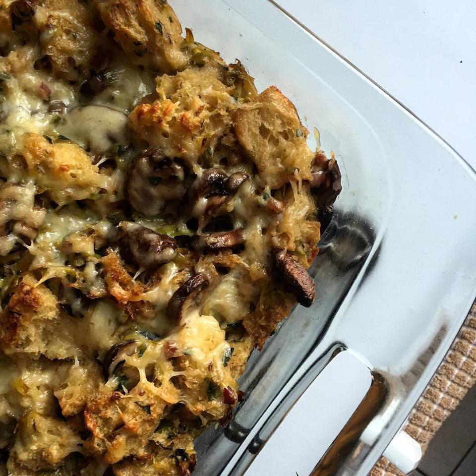 Golden-brown mushroom and leek bread pudding in a glass pan