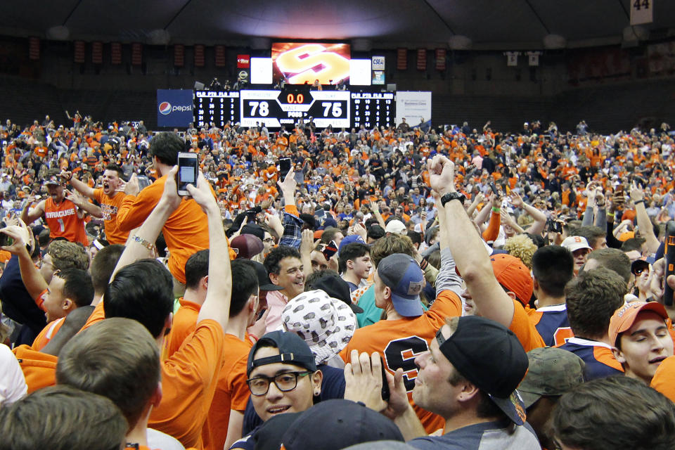 FILE - In this Feb. 22, 2017, file photo, Syracuse fans celebrate on the court after beating Duke in an NCAA college basketball game in Syracuse, N.Y. The virus that causes COVID-19 is most easily spread when an infected person coughs, sneezes or talks, allowing droplets to land in the mouths or noses of people nearby. That's why most recent guidelines from the Centers for Disease Control continue to preach 6 feet of separation in public setting as among the most important ways to stop the spread. (AP Photo/Nick Lisi, File)