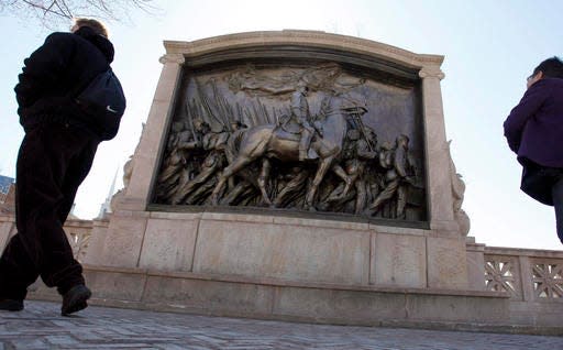 People walk past the memorial to Union Col. Robert Gould Shaw and the 54th Massachusetts Volunteer Infantry Regiment, near the State House in Boston.