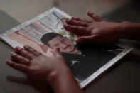 In this Feb. 13, 2020 photo, Alondra Mora runs her hands over a picture of her late husband, Miguel Flores Lopez, as she talks about his disappearance, during an interview in the two-bedroom home where they lived with their four children, in Irapuato, Guanajuato state, Mexico. Mora experienced first-hand Guanajuato's willingness to ignore the killings of poor migrants from other states. "When I went to file the missing person report, the guy who took my statement was making fun of us for being from Michoacán, saying 'Why did you have to come here?'" she recalled. (AP Photo/Rebecca Blackwell)