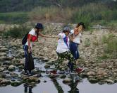 Mujeres cruzan el río Táchira en la frontera entre Venezuela y Colombia para asistir al concierto de Venezuela Aid Live en el lado colombiano de la frontera, en Palotal, Venezuela, el viernes 22 de febrero de 2019. (AP Foto/Fernando Llano)