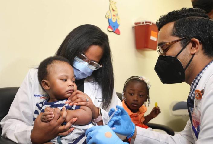 Dr. Nizar Dowla, right, gives a COVID-19 vaccine to Deji Adebayo, 9 months old, while his mother, Dr. Emy Jean-Marie, and his sister, Emiola Adebayo, 3, watch. Jean-Marie is a doctor at Borinquen Health Care Center in Miami, where the assistant secretary for health at the U.S. Department of Health and Human Services, Rachel Levine, and Miami-Dade Mayor Daniella Levine Cava attended the vaccine drive on Tuesday, June 28, 2022.
