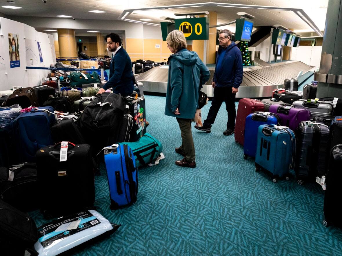 Passengers search for their luggage at Vancouver International Airport on Thursday. Federal Conservative Leader Pierre Poilievre is calling for tougher rules for airlines, saying the airport chaos over the holidays was not acceptable.   (Justine Boulin/CBC - image credit)