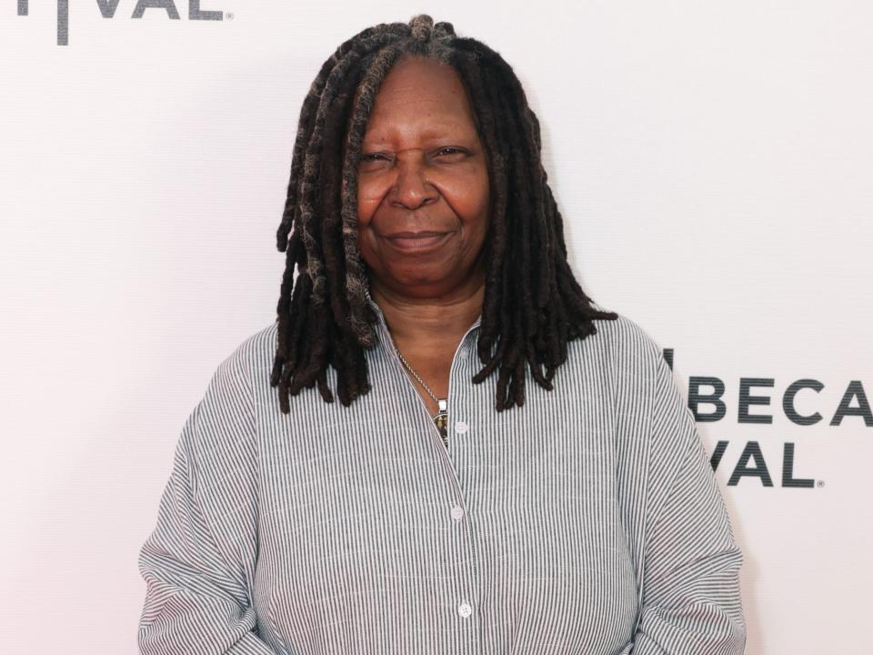 Whoopi Goldberg poses for photos in a striped shirt dress.