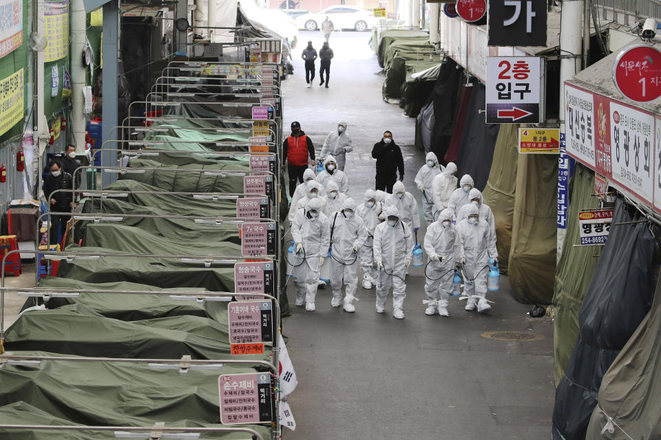 Workers wearing protective gear spray disinfectant as a precaution against the COVID-19 coronavirus in a local market in Daegu, South Korea, Sunday, Feb. 23, 2020. South Korea's president has put the country on its highest alert for infectious diseases and says officials should take "unprecedented, powerful" steps to fight a viral outbreak. (Im Hwa-young/Yonhap via AP)