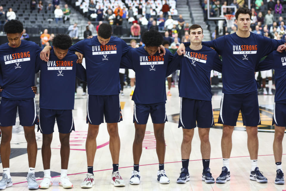 Viirginia players stand for the national anthem while wearing shirts in memory of the three students left dead in a shooting nearly a week ago, before the team's NCAA college basketball game against Baylor on Friday, Nov. 18, 2022, in Las Vegas. (AP Photo/Chase Stevens)