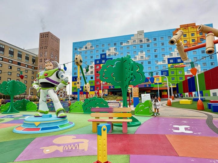 The colorful exterior of the Toy Story Hotel, located near the theme parks at Tokyo Disney Resort. The setting includes and oversized Buzz Lightyear statue and other colorful toy-inspired elements.