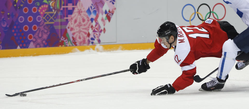 Austria forward Michael Raffl dives for control of the puck against Finland in the first period of a men's ice hockey game at the 2014 Winter Olympics, Thursday, Feb. 13, 2014, in Sochi, Russia. (AP Photo/Julio Cortez)