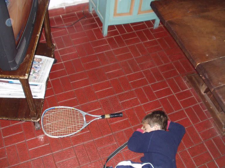 Navone y una situación repetida durante su infancia: dormido en el piso, junto a una raqueta y frente a la TV, con un partido de tenis de fondo