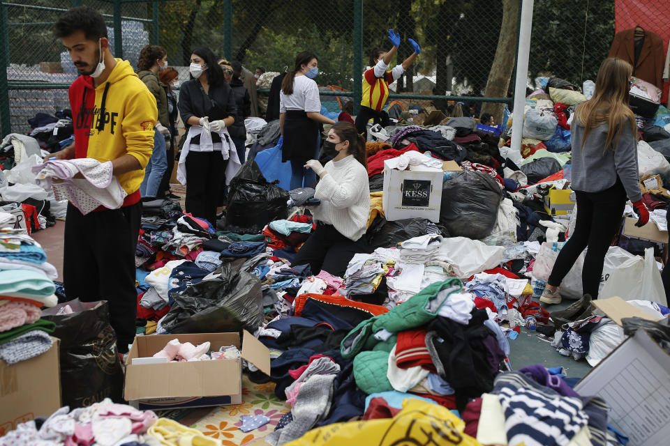 People who became homeless due to the earthquake go through handout clothes at a basketball court where tents for the homeless families had been set up, Izmir, Turkey, Tuesday, Nov. 3, 2020. Rescuers in the Turkish coastal city pulled a young girl out alive from the rubble of a collapsed apartment building Tuesday, four days after a strong earthquake hit Turkey and Greece. (AP Photo/Emrah Gurel)