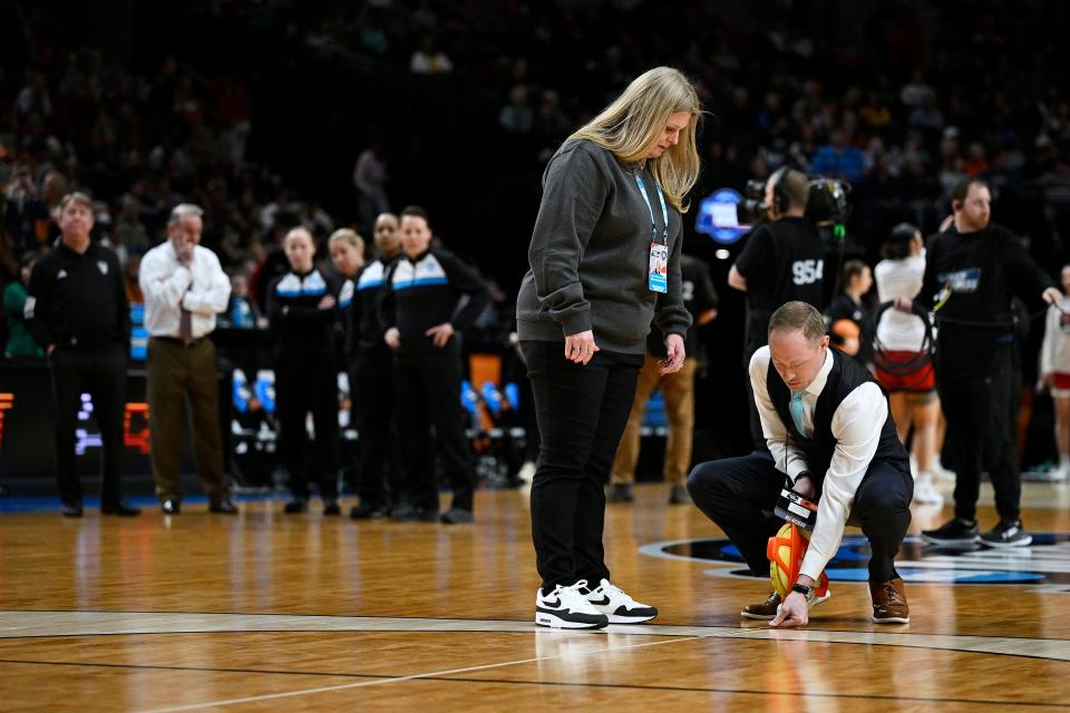 NCAA officials measure the three point line while coaches from the Texas Longhorns and NC State Wolfpack watch with referees in the finals of the Portland Regional of the NCAA Tournament at the Moda Center center. The teams played despite uneven lines. The NCAA has since apologized and fixed them ahead of Monday's Elite Eight games.