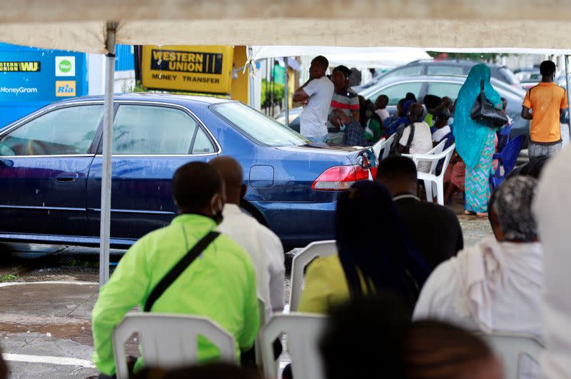 Customers sit under tent canopies outside a bank in area 8, in Abuja