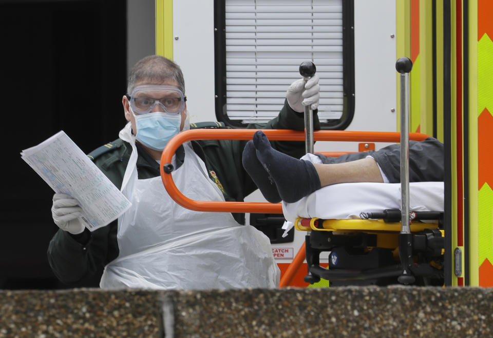 FILE - In this Tuesday, March 31, 2020 file photo a patient is helped from an ambulance as they arrive at St Thomas' Hospital, one of may hospitals that are in the front line of the coronavirus outbreak, in London. The U.K. has a lot to reflect on a year after British Prime Minister Boris Johnson first announced that the country would be put into a lockdown to deal with the fast-spreading coronavirus. It has seen more than 126,000 coronavirus-related deaths, more than any other in Europe and the fifth highest worldwide. (AP Photo/Kirsty Wigglesworth, File)