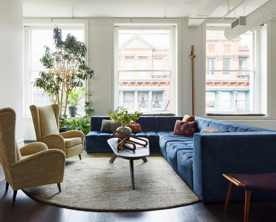 A custom sectional finished in Fabricut velvet sits opposite Italian midcentury armchairs upholstered in a Pollack fabric in a second living room seating area. The vintage William Haynes cocktail table and Beauvais circular rug help break up the linearity.