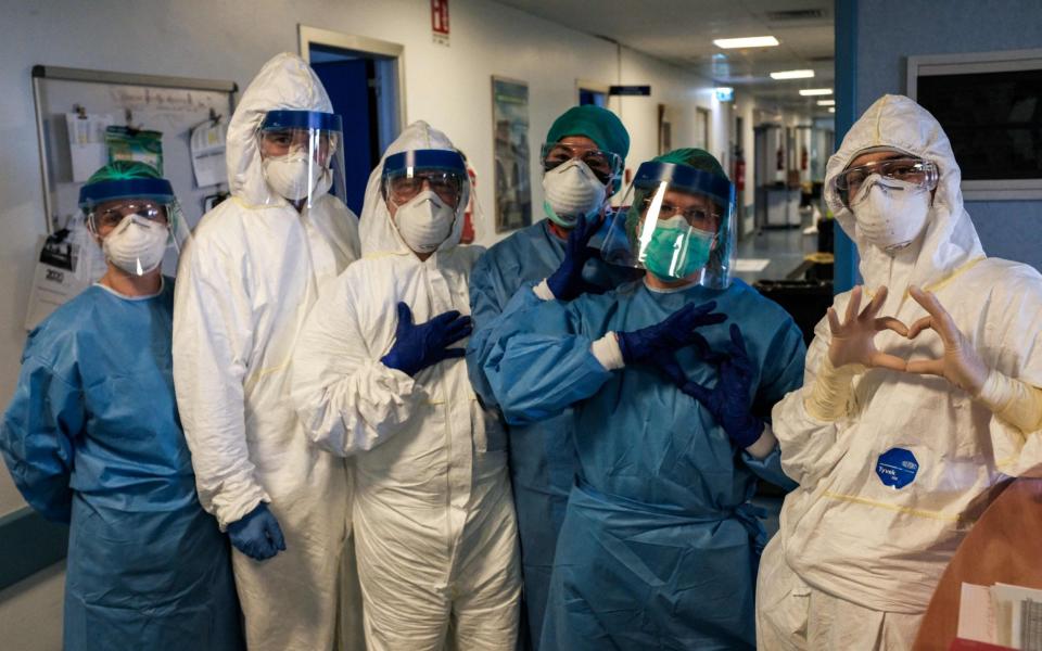 A group of nurses wearing protective gear pose for a group photo prior to their night shift at the Cremona hospital, southeast of Milan, Lombardy - AFP