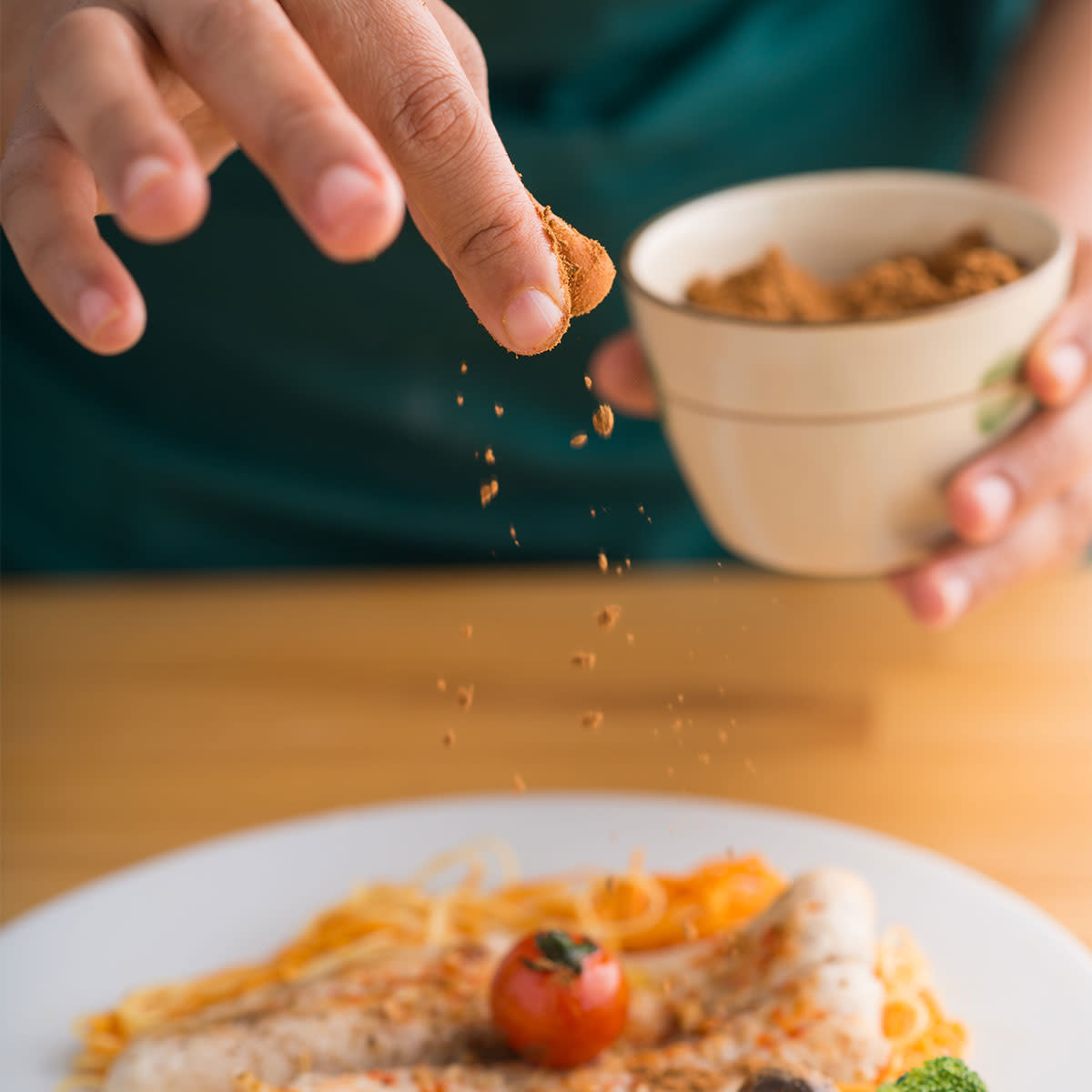 fingers sprinkling spices